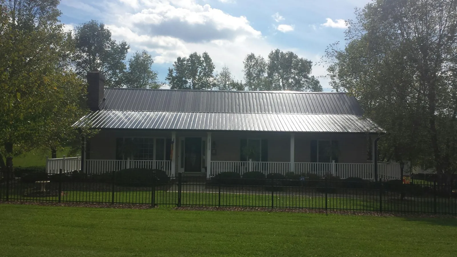 Gray metal roof on a brick ranch with a full width front porch — Gutter Guard Installation work by our crew in Alamo
